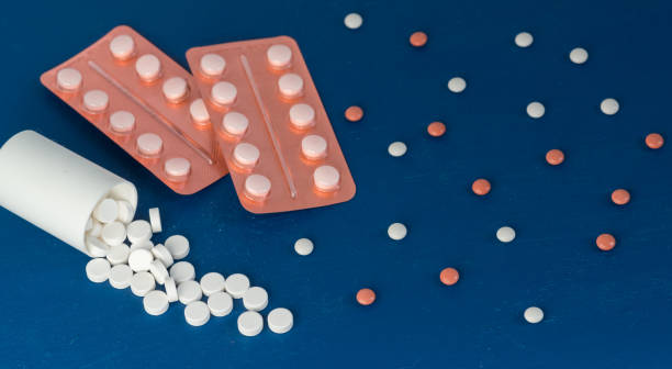 istock Scattered white and brown tablets in blisters on a blue background. Pharmaceuticals for the treatment of coronavirus. Copy space 1219966212