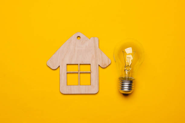 istock Save energy concept. Mini house, incandescent light bulb on yellow background. Top view 1219966358