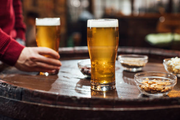 glasses of beer and peanuts on a wooden table at a pub, a close up - beer nuts imagens e fotografias de stock