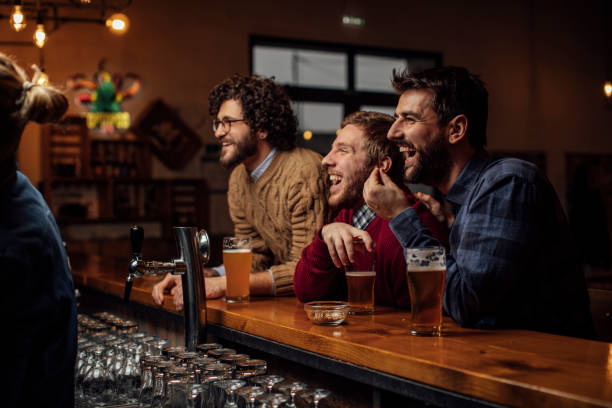 group of happy young men drinking beer and watching a soccer game at the pub - club soccer fotos imagens e fotografias de stock