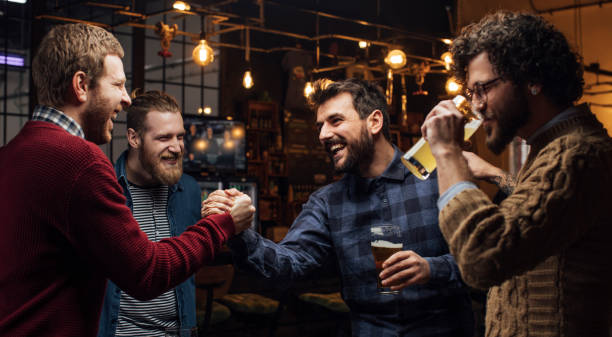 hombre saludando a sus compañeros en el pub - beer nuts fotos fotografías e imágenes de stock