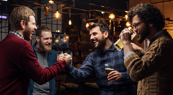Men at social gatherings: group of friends drinking beer at the pub together.