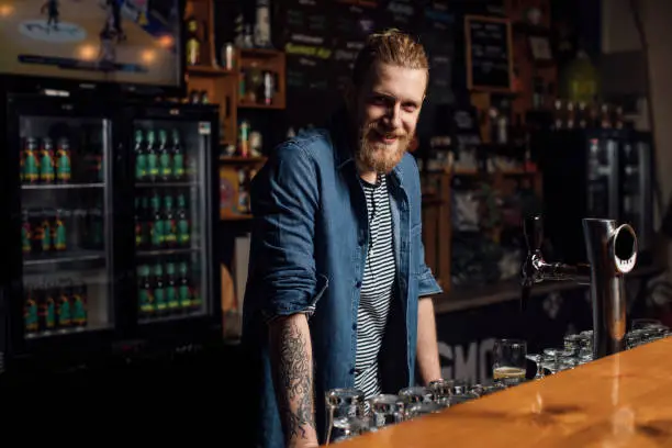 Happy bartender ready to serve customers, looking at camera.