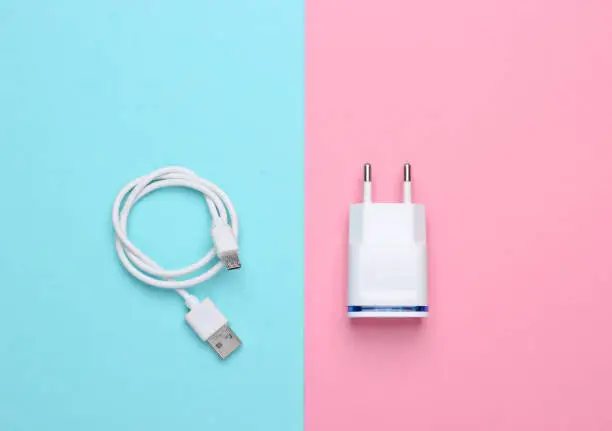 Photo of Charger with cable on pink blue pastel background. Top view