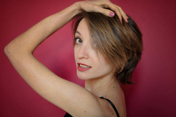 jeune femme avec le cheveu court rectifié dans le bustier noir de dentelle et le jean bleu pose dans le studio sur le fond rose lumineux - fashionable the human body short hair human head photos et images de collection