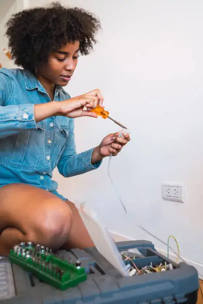 Portrait of young afro woman fixing something with a screwdriver at home. Repair and renovation home concept.