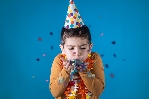 Little kid blowing confetti in his birthday