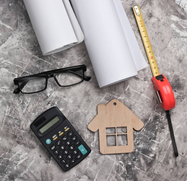 istock Engineer workspace. Construction helmet, rolls of drawings, calculator and glasses, ruler on gray concrete background. House building. Top view. 1219968788