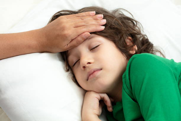 istock Mother checking on sick her son laying in bed 1219970683