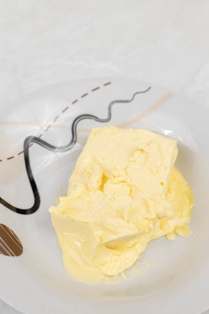 Block of butter.  Fresh, ready to eat butter on ceramic dish with table knife, from above on white background.