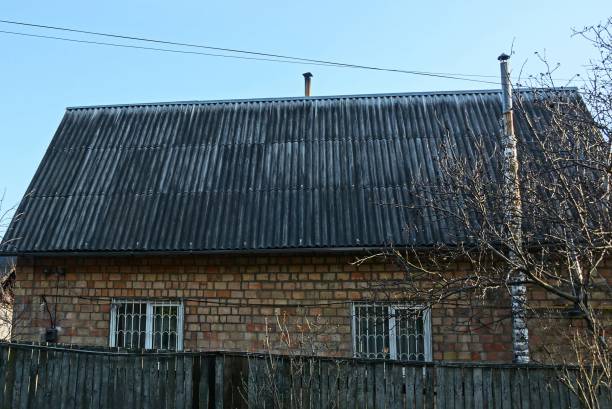 private house of brown bricks with windows under a gray slate roof against a blue sky