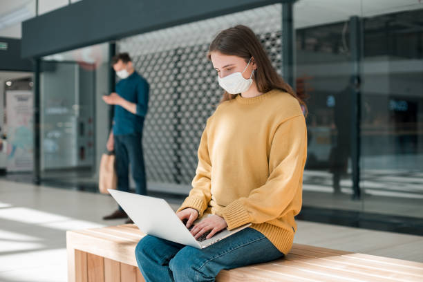 female blogger in a protective mask works on a laptop