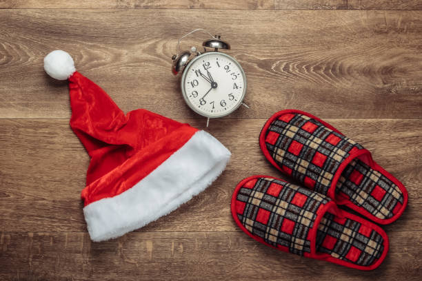 istock Christmas concept. Santa hat, sleeping slippers, alarm clock on the floor. Top view 1219974014