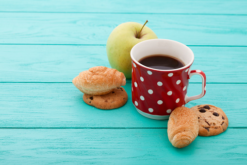 Cup of coffee with croissants on blue wooden table. Selective focus and top view