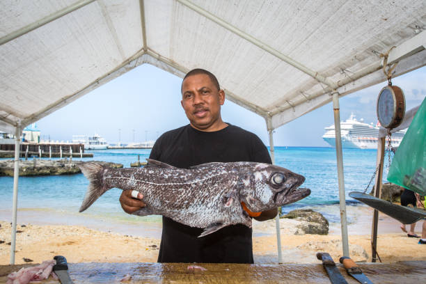 uomo che tiene il pesce al mercato del pesce, george town, isole cayman - fish catch of fish seafood red snapper foto e immagini stock