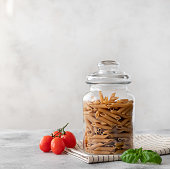 Wholewheat penne pasta in a glass container.
