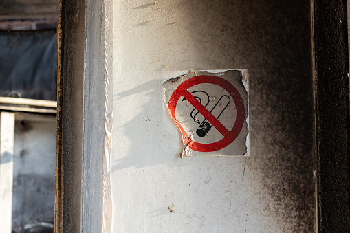 molten sticker with a no smoking sign on the wall with traces of black soot from a fire.