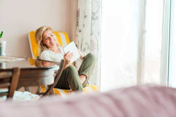 istock Young woman holding digital tablet by window 1219983993