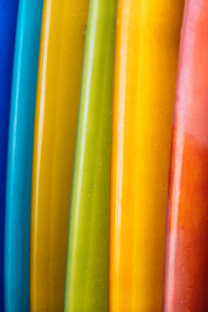 Close up Set of different color surf boards in a stack on sandy beach for rent. Multicolored surfboards as rainbow