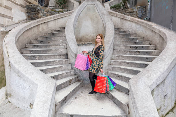 幸せな笑顔でカラフルなショッピングバッグを持っている若い女性。トルコ・イスタンブールのガラタ地区にあるカモンド階段(トルコ語:カモンド・メルディゼンレリ)。 - camondo ストックフォトと画像