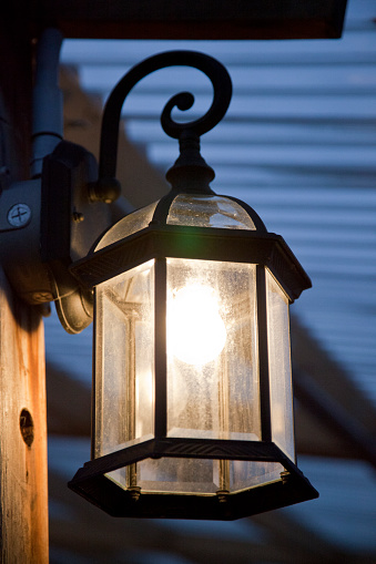 Illuminated rustic lantern on the porch. Bright decorative lamp by the front door.