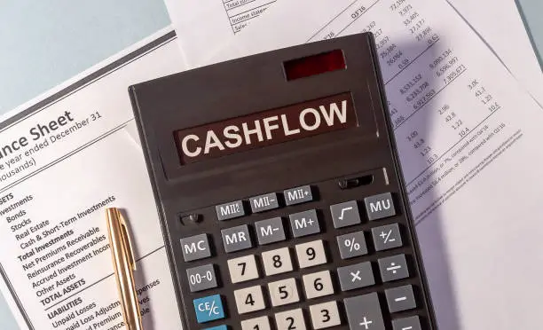 Photo of CASHFLOW word on calculator and pen on documents