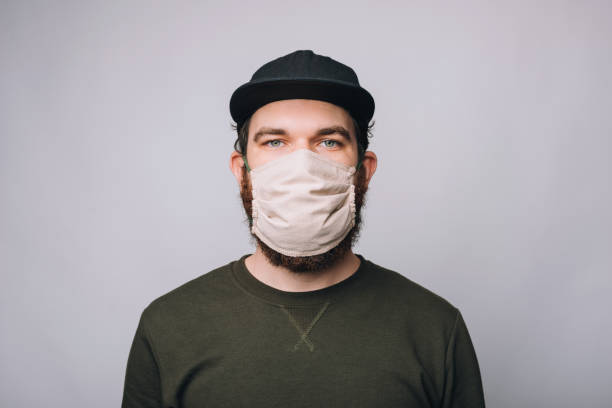istock bearded hipster man standing over white wall and wearing facial mask for virus 1219993473
