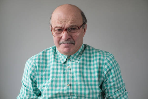 Senior Caucasian man against white backdrop. He is dressed in casual clothes.