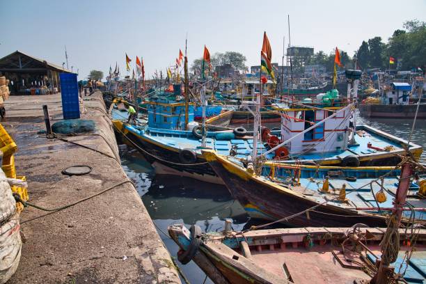 Mumbai, India - January 06, 2020: Colorful boats with flags on the water, near the shore at Sassoon Dock in Colaba district, in the middle of a sunny beautiful day, in Mumbai, India.