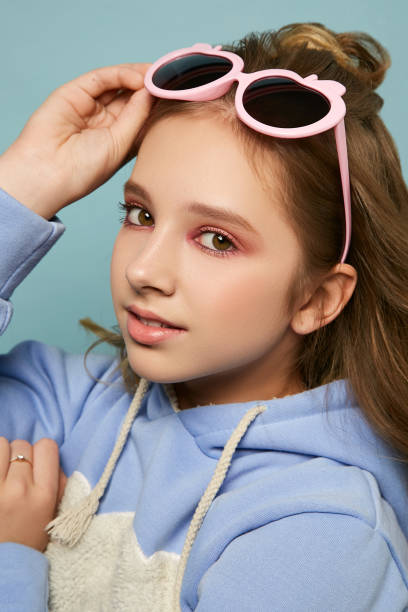 istock Beautiful young girl with bright makeup. Model with glasses posing in the studio on a blue background 1219999727
