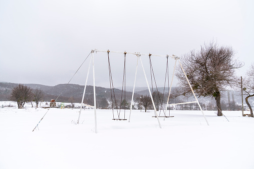 Empty Stage. Park, swing, snow in winter time. Mountain view