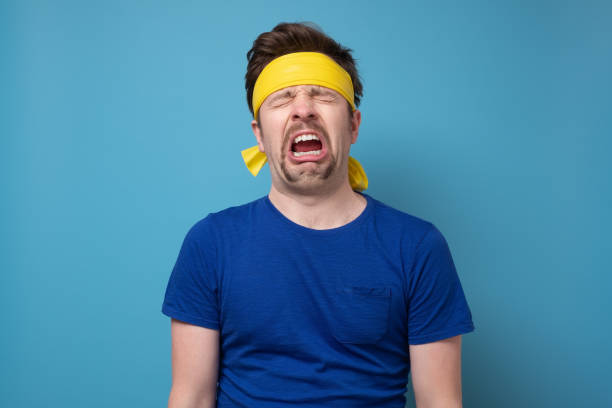 Young caucasian sport man with yellow rubber band whining and crying stock photo