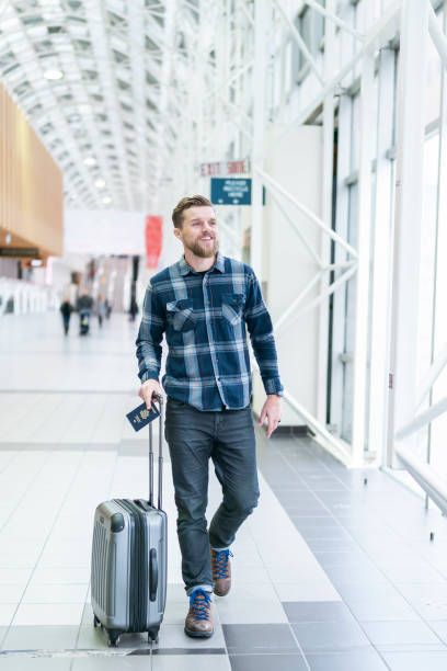 istock Man traveling internationally walking with luggage through airport 1220002933