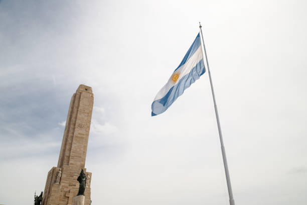 drapeau argentin devant la tour du monument national de drapeau à rosario, argentine - place mat photos et images de collection