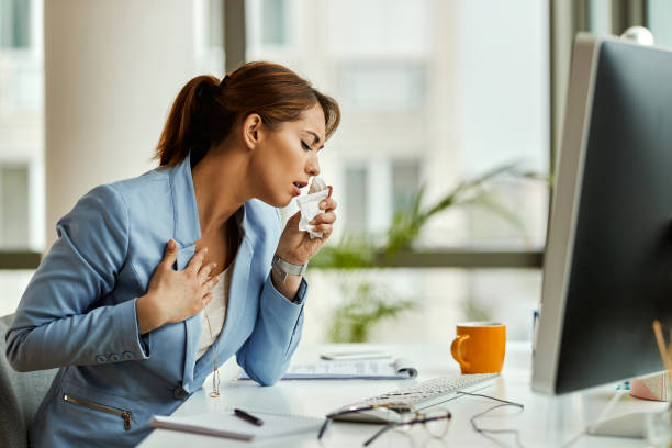 istock Young businesswoman coughing while working on desktop PC in the office. 1220007165