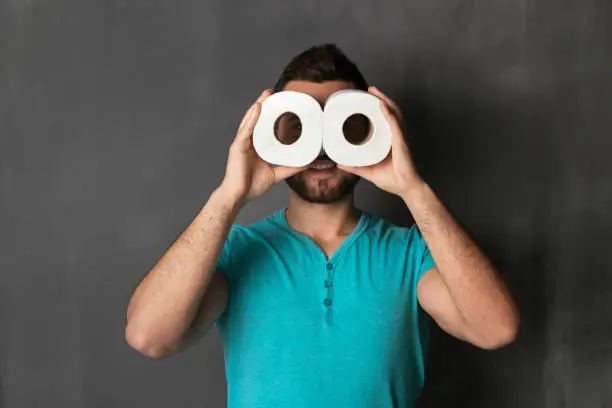 Handsome guy looks through rolls of toilet paper and simulating binoculars
