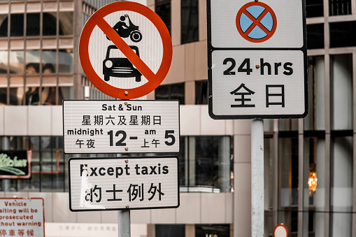 Road signs No cars or motorcycles, No stopping with bilingual descriptions. Writing system on the traffic signs comprises British English and traditional Chinese, two official languages of Hong Kong, in an order of English above Traditional Chinese.