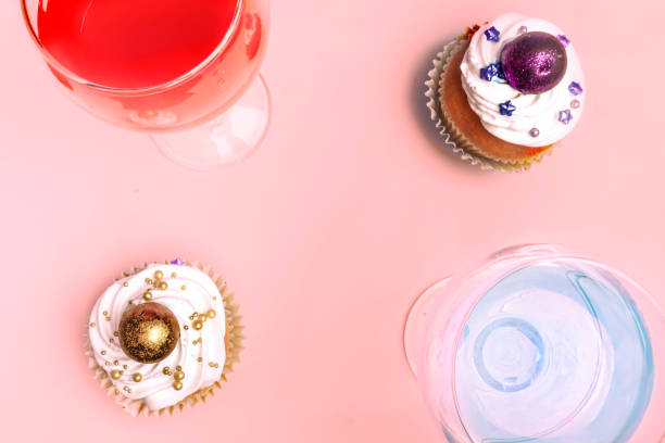 Sweet, colorful cupcakes decorated with sugar paste and cream with two glass of sweet water. Concept of art paty. Flat lay, top veiw.