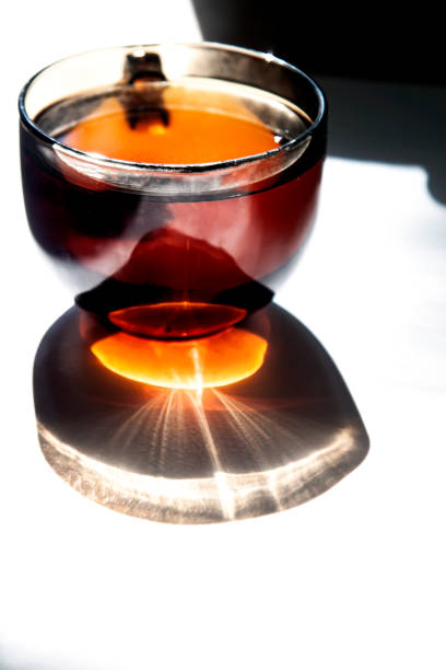 A large cup of tea casts a curly shadow on the table.