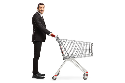Full length profile shot of a businessman with an empty shopping cart isolated on white bacakground