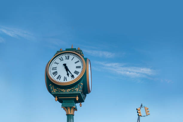 istock looking up at a big clock and traffic light at a distance. Blue sky with wispy clouds 1220016139