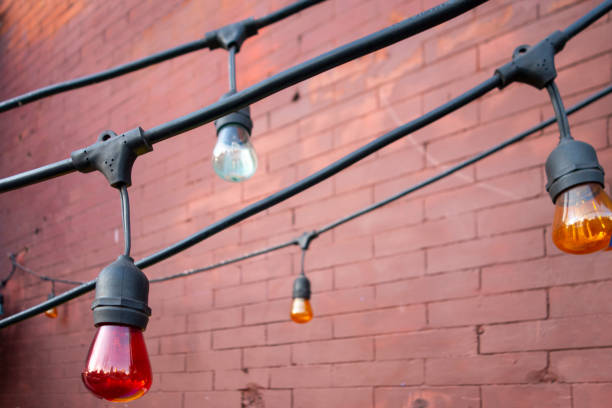 istock Lighting decorations of colored big light bulbs hanging down from thick black electrical wire 1220016198