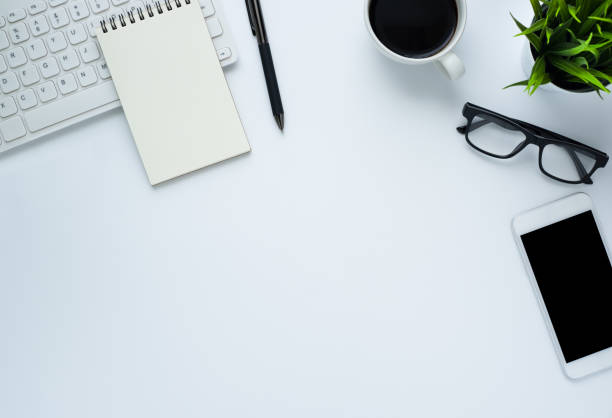 istock Workplace in office with white desk. Top view from above of keyboard with notebook and coffee. Space for modern creative work of designer. Flat lay with blank copy space. Business and finance concept. 1220029758