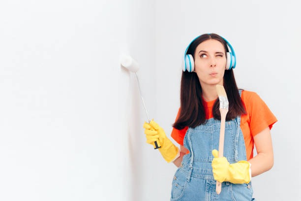 funny woman painting the wall listening to music with headphones - home addition audio imagens e fotografias de stock