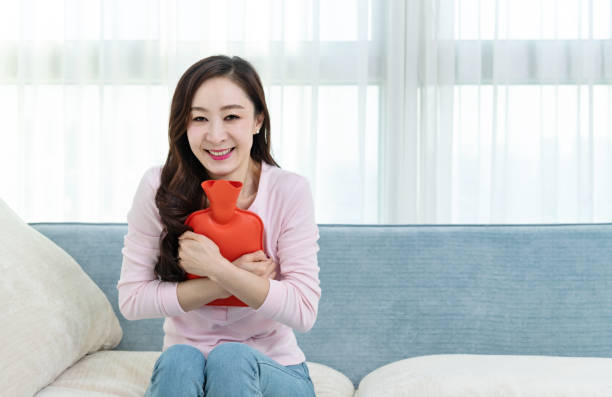 istock Woman sitting on sofa with hot water bottle 1220039400