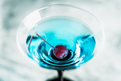 Blue martini cocktail with cherry on the rustic background. Selective focus. Shallow depth of field.