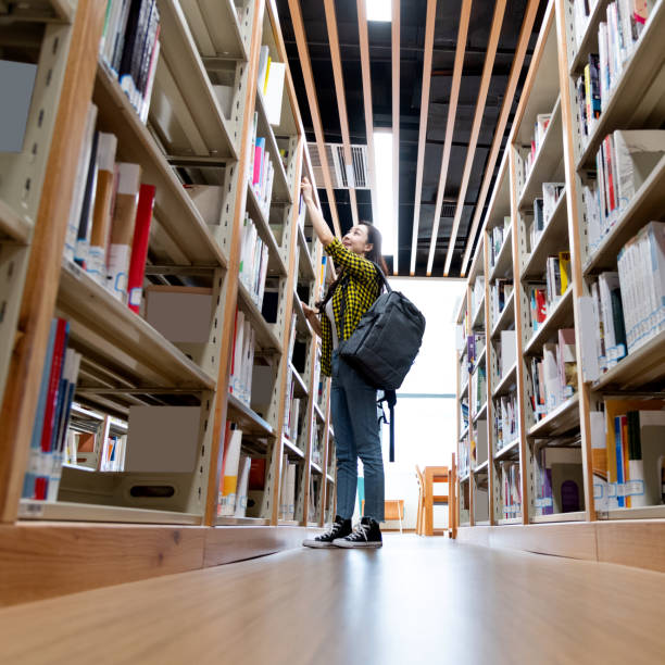 istock Beautiful woman choosing book in the library 1220043502