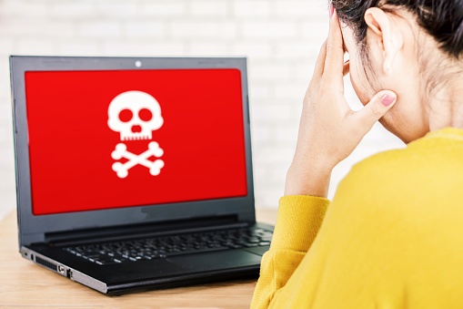 upset Asian business woman with computer screen showing virus warning alert, hacking,piracy and security concept