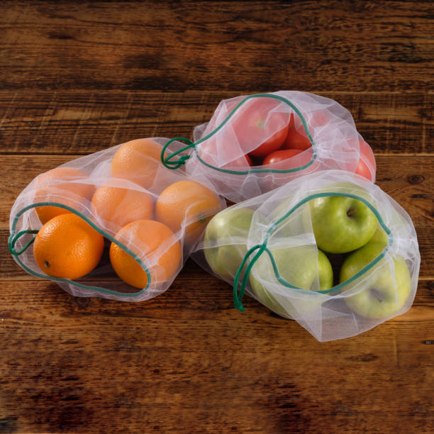 istock Zero waste, plastic free recycled textile produce bag for carrying fruit apple, orange, tomatos or vegetables, a wooden surface. Reusable using. 1220050024
