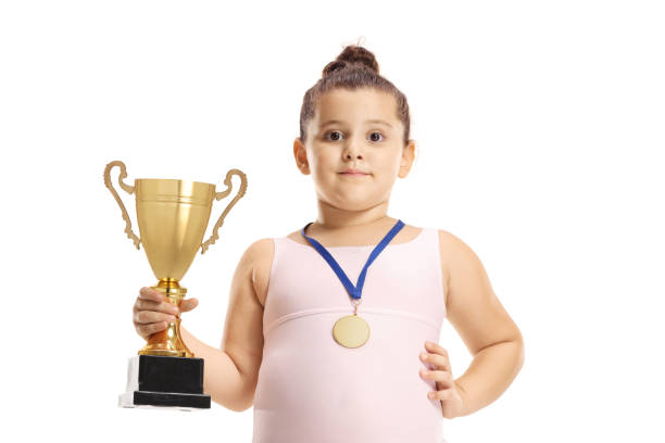 little gymnastics girl holding a gold trophy cup and a medal - gymnastics smiling little girls only isolated on white imagens e fotografias de stock